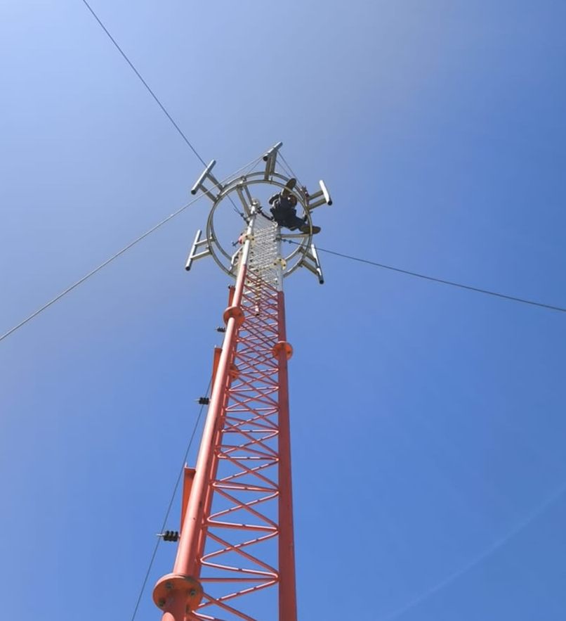 Técnico trabajando en la cima de una torre de telecomunicaciones
